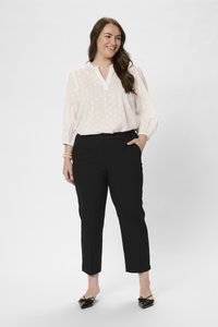 Weiße, gepunktete Bluse mit Kragen, kombiniert mit schwarzen, taillierten Hosen und schwarzen Ballerinas mit Schleifenakzenten. Glatte Texturen, klare Linien.