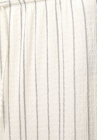 Tessuto intrecciato con uno sfondo bianco testurizzato e sottili righe verticali blu. Il materiale è leggero e offre un sottile contrasto di pattern.