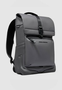 Grauer Rucksack mit strukturierter Form, matter Oberfläche, äußerer Reißverschlusstasche, Griff oben und gepolsterten Trägern für Komfort.