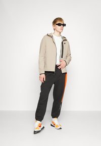 Calvin Klein Jeans STACKED PANT - Spodnji deli trenirk - black/coral orange