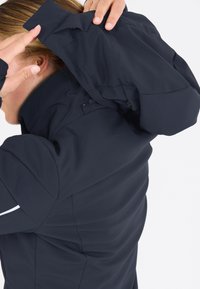 Marineblå softshell-jakke med et tætsiddende design og høj krave. Har en lynlåse hætte og glat tekstur, velegnet til udendørs brug.