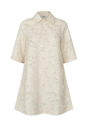 Túnica tipo polo de manga corta en color crema claro con un patrón texturizado, que presenta un cuello clásico y una silueta amplia tipo línea A.