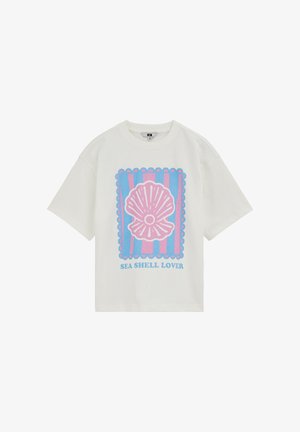 Fehér rövid ujjú ing rózsaszín tengeri kagyló grafikával, kék és rózsaszín csíkok keretezik, az "SEA SHELL LOVER" szöveg a kép alatt.
