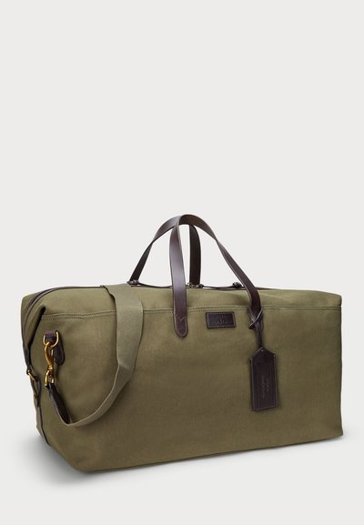 Borsa duffel rettangolare verde oliva con manici in pelle marrone, tracolla staccabile e targhetta in pelle su sfondo semplice.