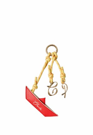 Porte-clés en cuir rouge avec cordons noués jaunes et breloques lettres dorées "C" et "T" attachées à un anneau porte-clés doré.