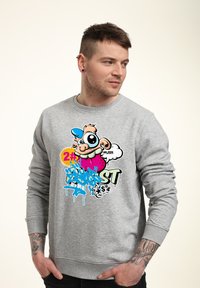 Grijze sweatshirt met een kleurrijk grafisch ontwerp van een cartoonfiguur, spatten van blauw en roze, en zwarte lettering. Gemaakt van katoen.