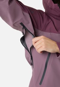 Vandtæt jakke i mauve med sorte lynlåsdetaljer. Har en brystlomme og justerbare manchetter. Glat tekstur, designet til udendørs brug.