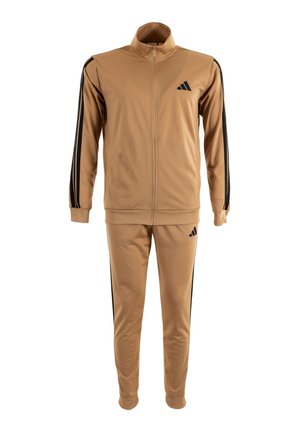 Tuta beige con strisce nere sulle maniche e sui pantaloni, giacca con zip a tutta lunghezza e colletto alto, e logo nero sul petto e sulla coscia.