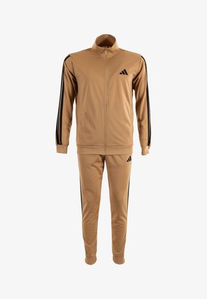 Tuta beige con strisce nere sulle maniche e sui pantaloni, giacca con zip a tutta lunghezza e colletto alto, e logo nero sul petto e sulla coscia.