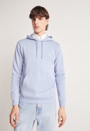 Helleblaue Kapuzenjacke aus weichem Stoff, mit Kordelzug, vordere Kängurutasche und gerippten Bündchen und Saum. Getragen mit hellen Jeans.