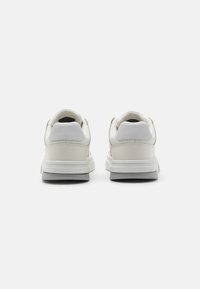 Witte leren sneakers met een gladde textuur, voorzien van een gevoerde kraag, grijze rubberen zool en een minimalistisch ontwerp. De achteraanzicht toont de stikseldetails.