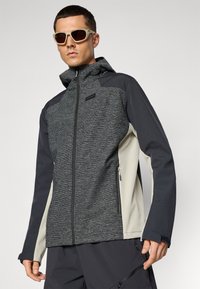 Men's zip-up jacket featuring a grey textured front, dark sleeves, and light accents. Designed with a hood and side pockets.