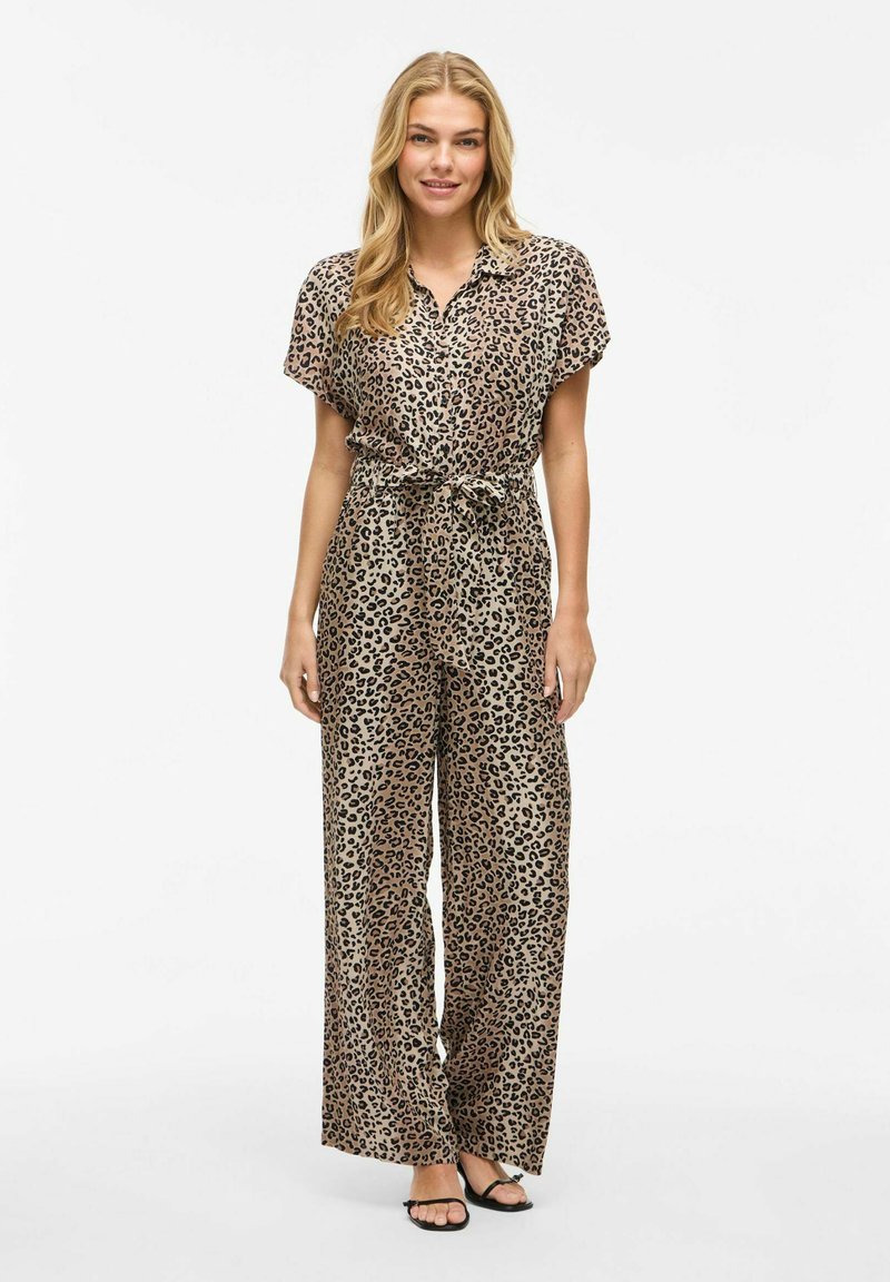 Combinaison à imprimé léopard avec des manches courtes, fermeture à boutons, taille cintrée et pantalons à jambes larges en tissu lisse dans des tons de tan et de noir.