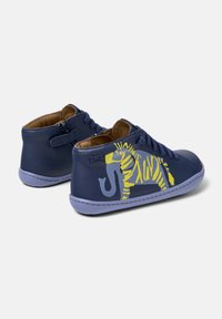 Baskets en cuir pour enfants bleu marine avec des semelles violettes, des lacets et un graphique d'éléphant jaune et gris sur le côté.