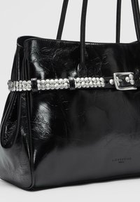 Czarna skórzana torebka o pomarszczonej fakturze, z paskiem ozdobionym perłami i srebrną klamrą. Wytłoczone logo marki "LIEBESKIND".