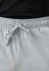 Light gray sweatpants with a drawstring closure, elastic waistband, smooth texture, and two front pockets visible at the bottom.