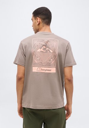 Vyras dėvi taupe spalvos trumpomis rankovėmis marškinėlį su persikų spalvos geometriniu kalnų ir lauko grafikos atvaizdu bei „berghaus“ logotipu ant nugaros.