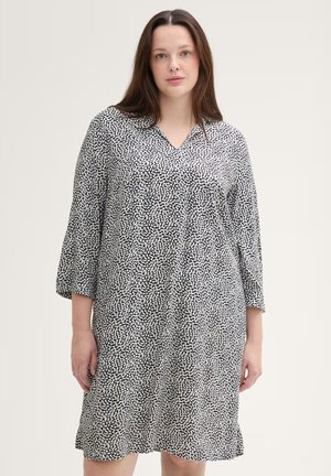 Abito in bianco e nero con scollatura a V, maniche 3/4 e un motivo astratto. Tessuto leggero con una vestibilità comoda, che arriva sopra al ginocchio.