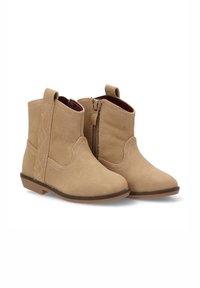 Botines de ante en tono marrón claro con tacón bajo, que cuentan con un cierre lateral y costuras decorativas en la parte superior. Textura suave y punta redondeada.