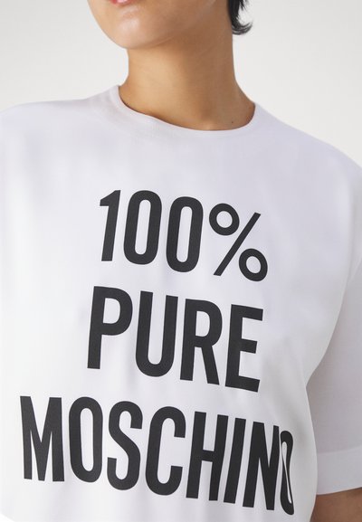 Tricou alb din bumbac, cu text negru îndrăzneț "100% PURE MOSCHINO" și grafică cu un ac de siguranță, mâneci scurte și decolteu rotund.
