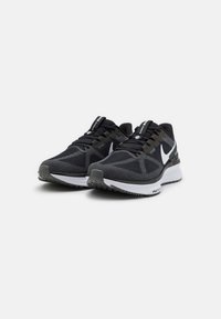 Scarpe sportive nere con tomaia in rete, logo Nike bianco, lacci testurizzati e colletto imbottito. Presentano una suola in gomma nera e grigia.