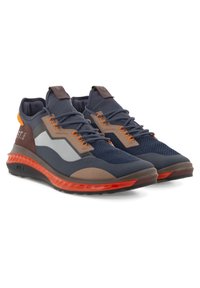 Paire de chaussures de sport bleu marine avec lacets orange et accents sur la semelle, détails latéraux marron et blanc, et colliers de cheville rembourrés.