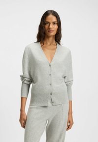 Light gray cardigan made of soft material, featuring a V-neck, long sleeves, and front buttons. Smooth texture with ribbed accents.