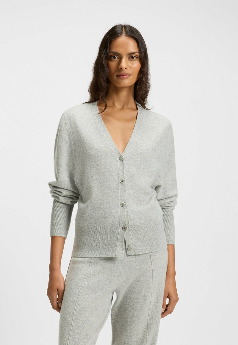Light gray cardigan made of soft material, featuring a V-neck, long sleeves, and front buttons. Smooth texture with ribbed accents.