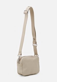 Beige schoudertas van gestructureerd materiaal, met een rechthoekige vorm, verstelbare schouderriem en zilverkleurige hardwareaccenten.