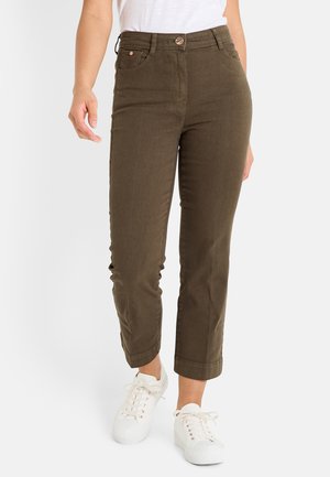 Pantalons vert olive à jambe droite avec une fermeture à bouton à l'avant, cinq poches et ourlets retroussés, associés à des baskets blanches.