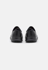 Schwarze Slipper mit niedrigem Profil, strukturiertem Lederobermaterial und flexibler Gummisohle; mit kleinen Zuglaschen an der Ferse für ein einfaches Anziehen.