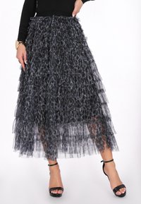 Sort lagdelt nederdel lavet af gennemsigtigt, let materiale med leopardmønster. Har flere volanger, ankel-længde design og en tætsiddende talje.