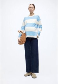 Gaiši zils un krēmkrāsas svītrains džemperis, brīvas tumši dzeltenas džinsa bikses, bēša krāsas mules un brūna soma. Mīksts audums, plati piedurkņu gali un vaļējs siluets.