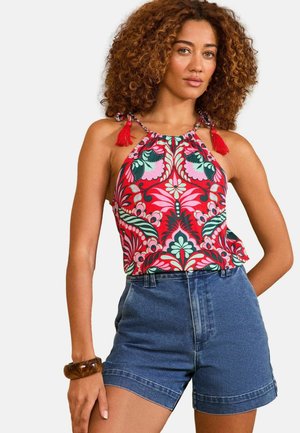 Haut à dos nu coloré avec des motifs floraux en rouge, vert et rose ; présente des franges sur les bretelles. Assorti à un short en denim taille haute.