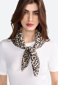 Bufanda de estampado de leopardo hecha de una tela ligera, atada alrededor del cuello, con un fondo beige y manchas negras y marrones.