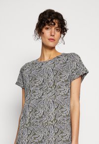 Vestido de manga curta em verde oliva com padrão de folhas brancas. Decote redondo, silhueta descontraída e textura de tecido macio.