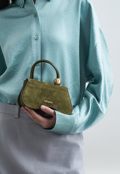 Πράσινη σουέτ τσάντα με στρογγυλή λαβή και χρυσή λεπτομέρεια. Η τσάντα διαθέτει καμπύλο, δομημένο σχέδιο και λογότυπο σε χρυσά γράμματα.