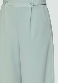 Lichtblauwe wijde broek met een geplooide voorkant, twee knopen op de tailleband en een subtiele textuur. Inclusief een klein logo detail.