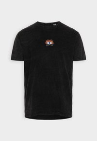Camiseta negra de manga corta con escote redondo, que presenta un gráfico colorido de un ojo y un diseño de ráfaga de sol con la palabra "KAOTIKO" debajo.
