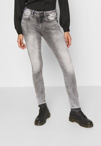 Jeans ajustados en un lavado gris desvanecido, con diseño de cinco bolsillos y trabillas para el cinturón. Combinados con botas de tobillo negras con cordones.