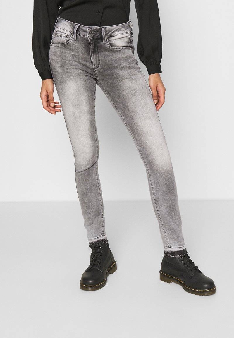 Jeans ajustados en un lavado gris desvanecido, con diseño de cinco bolsillos y trabillas para el cinturón. Combinados con botas de tobillo negras con cordones.