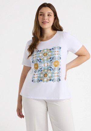 Camiseta blanca de manga corta con un intrincado patrón floral en azul, dorado y verde, con un diseño circular en el centro. Textura de tela suave.
