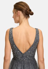 Graues Abendkleid mit tiefem V-Ausschnitt, verziert mit kleinen silbernen Perlen und floralen Mustern am Oberteil und den Trägern.