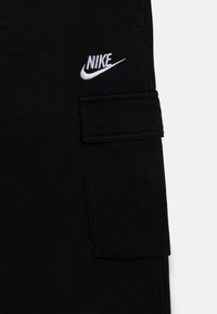 Sorte cargo bukser lavet af bomuldsstof med et fremtrædende hvidt Nike-logo. Har en sidelomme med klap og syning akcentueret.