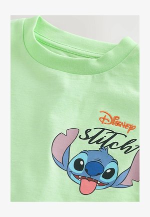 Tricou din bumbac de culoare verde deschis, cu un grafic al feței unui personaj de desene animate, având urechi roz, trăsături albastre și ochi negri, etichetat "Disney Stitch."