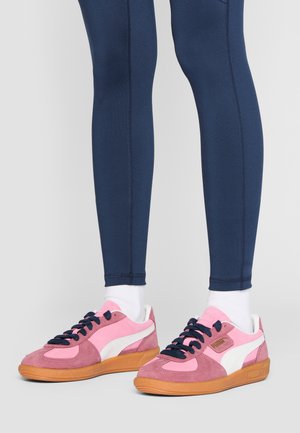 Puma-sneakers i pink og hvid ruskind med gummisål, der har navy snørebånd og en struktureret overflade. Leggings i navy strækstof.