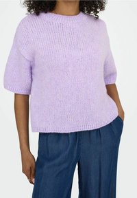 Maglione lilac lavorato a maglia con maniche corte e scollo rotondo. Tessuto morbido, vestibilità comoda e orlo a costine. Abbinato a pantaloni in denim scuro larghi.