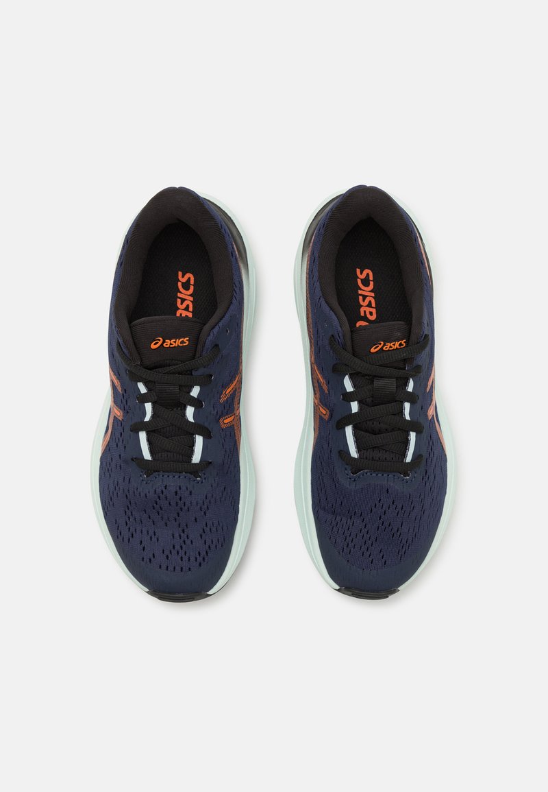 Baskets de sport navy avec des accents orange, tige texturée et lacets noirs. Elles présentent une semelle rembourrée verte menthe et un design ventilé.