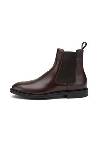 Bota Chelsea de cuero marrón con paneles laterales elásticos, punta redonda y suela de goma negra. Tirador en la parte trasera para facilitar su calzado.