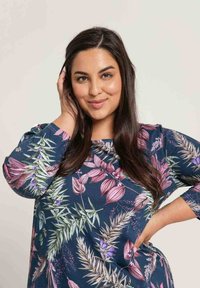 Granatowy top w kwiatowy wzór z rękawami do łokcia, ozdobiony różowymi i zielonymi motywami liści, wykonany z miękkiego, lekkiego materiału.